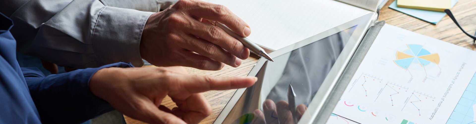 Digital tablet with financial report in hands of business partners